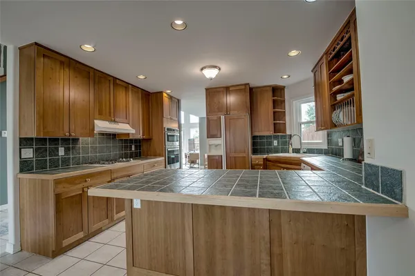 a kitchen with stainless steel appliances granite countertop wooden cabinets a stove and a sink
