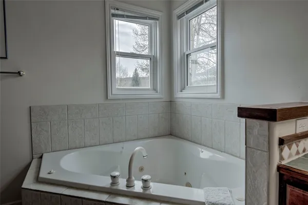 a white bath tub sitting in a bathroom next to a window
