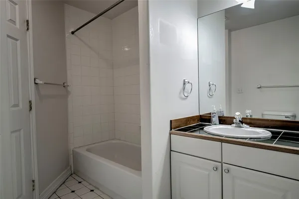 a bathroom with a granite countertop sink a mirror a bathtub and shower