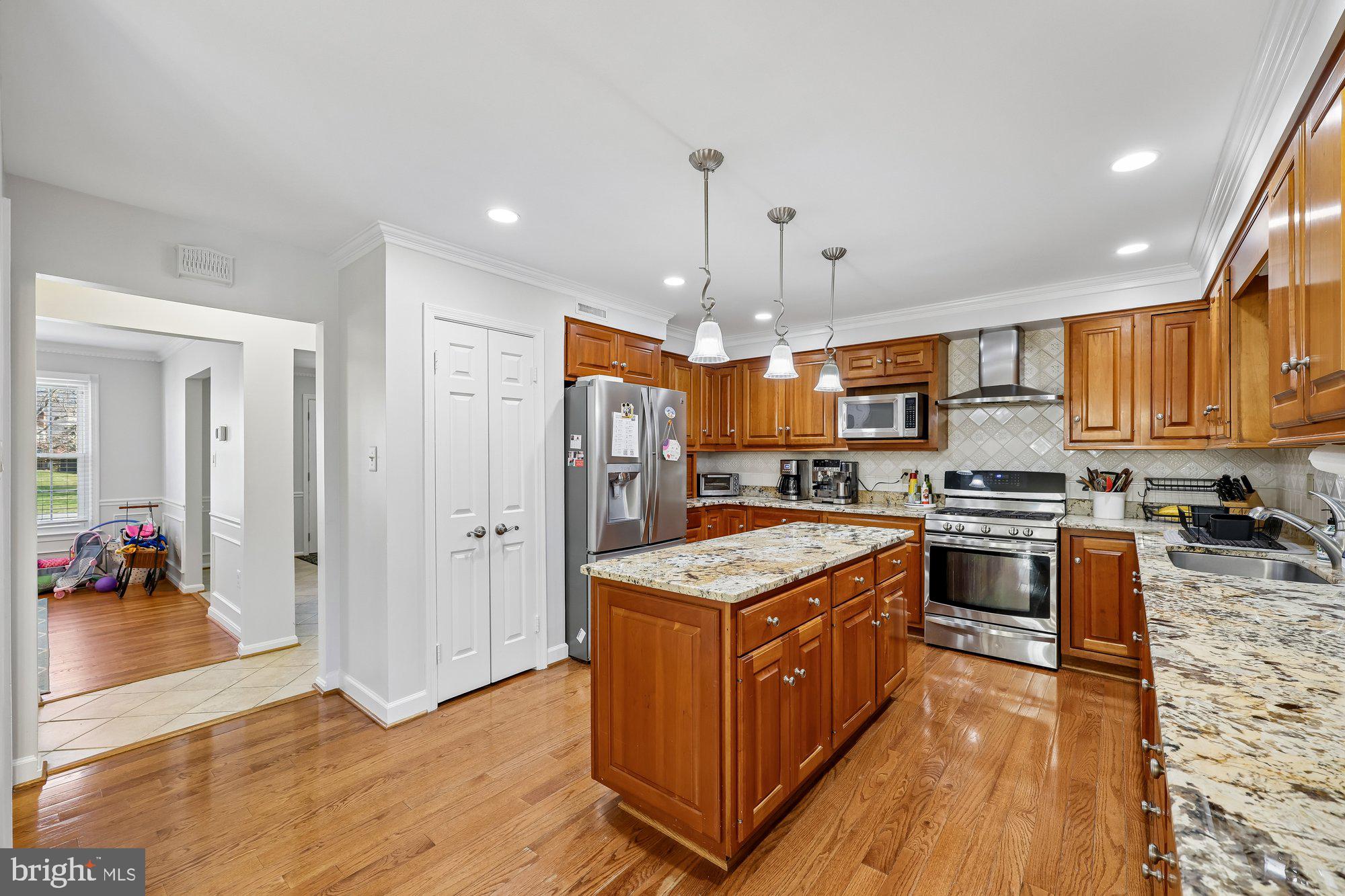 18 Kaywood Court Silver Spring, MD 20905 - Photo 22 of 71 a kitchen with stainless steel appliances granite countertop a stove a refrigerator a sink dishwasher and a dining table with wooden floor