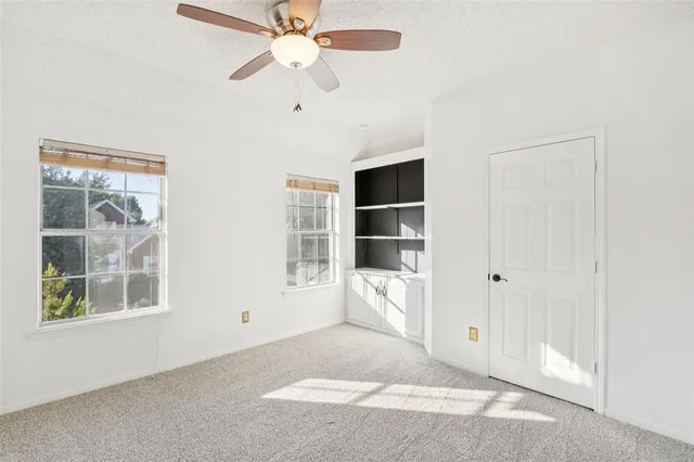 an empty room with windows and fan