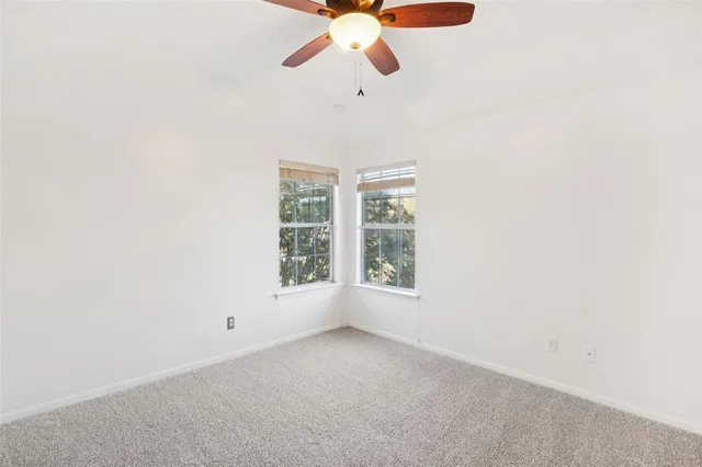 an empty room with windows and ceiling fan