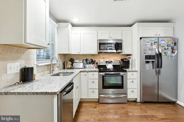 a kitchen with stainless steel appliances a sink dishwasher stove refrigerator and cabinets