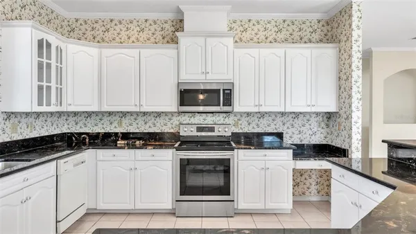a kitchen with stainless steel appliances granite countertop a sink a stove a dining table and chairs