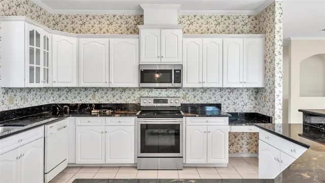 a kitchen with stainless steel appliances granite countertop a sink a stove a dining table and chairs