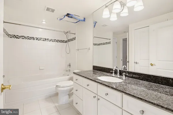 a bathroom with a granite countertop sink a toilet a mirror and shower