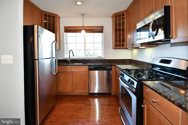 a kitchen with stainless steel appliances granite countertop a stove a refrigerator and a microwave