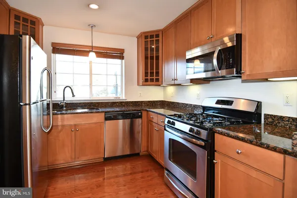 a kitchen with stainless steel appliances granite countertop a refrigerator a stove a sink and a microwave