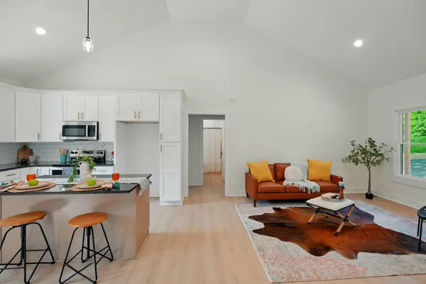 a living room with stainless steel appliances kitchen island granite countertop furniture and a wooden floor