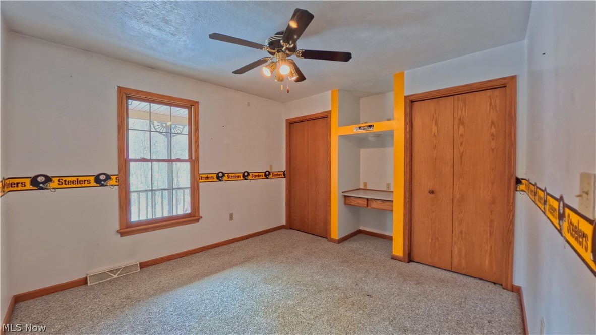48276 Dyke Road Negley, OH 44441 - Photo 22 of 30 Unfurnished bedroom with two closets, light colored carpet, and a ceiling fan