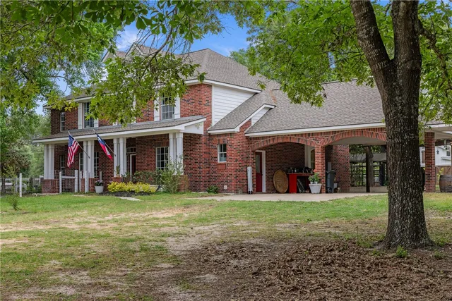 a view of a brick house with a yard in front of it
