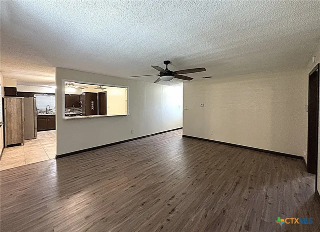 a view of a big room with wooden floor and a kitchen