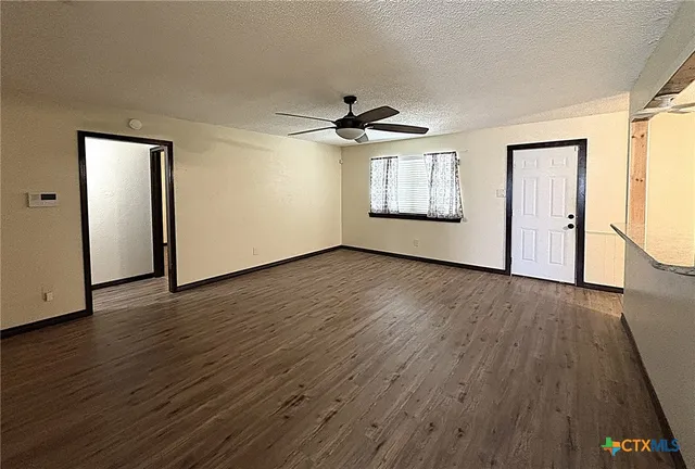 an empty room with wooden floor a ceiling fan and windows