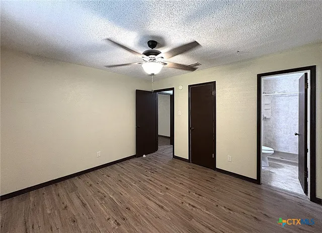 an empty room with wooden floor and ceiling fan