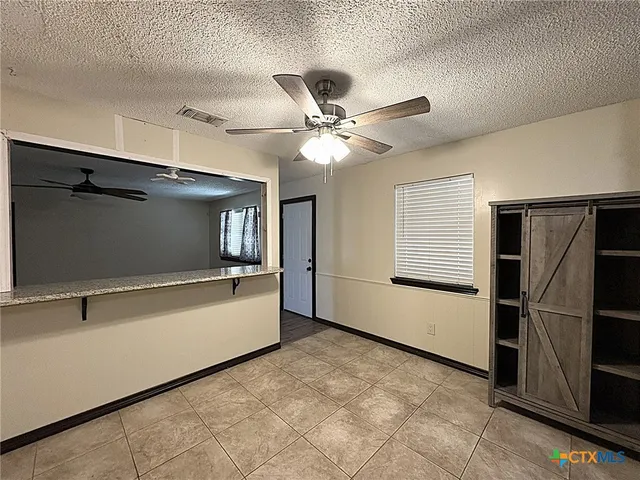 a view of a refrigerator in kitchen and empty room with wooden floor