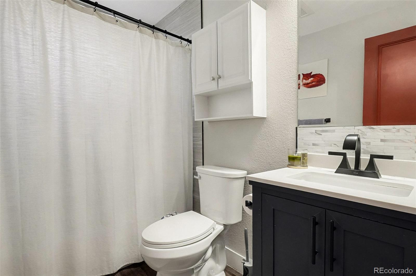 4784 Swadley Street Wheat Ridge, CO 80033 - Photo 17 of 22 a bathroom with a sink a toilet and a mirror