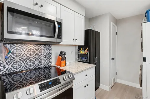 a kitchen with granite countertop white cabinets and stainless steel appliances