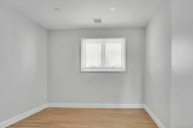 a view of a small space with wooden floor and a window