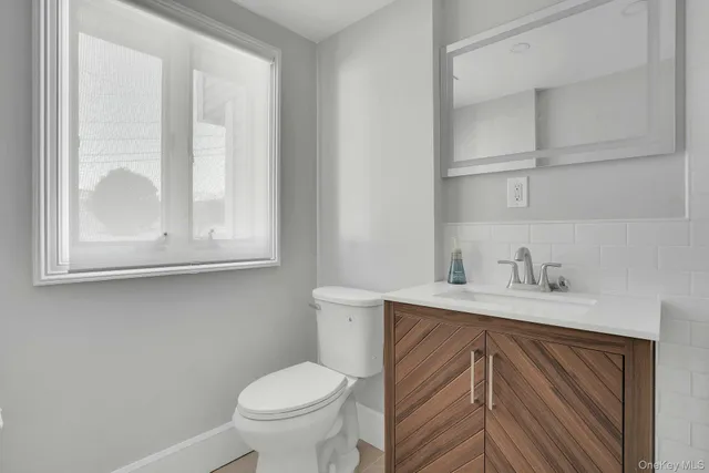 a bathroom with a toilet a sink a vanity and a window