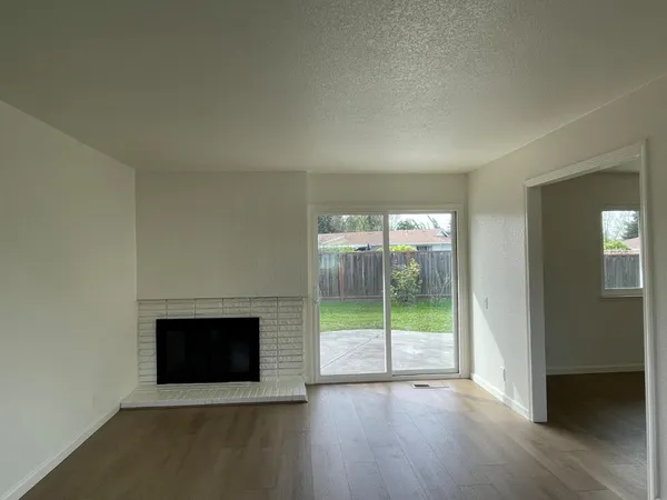 an empty room with wooden floor and fireplace
