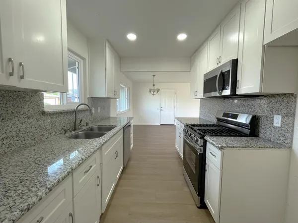 a kitchen with stainless steel appliances granite countertop a sink stove and refrigerator