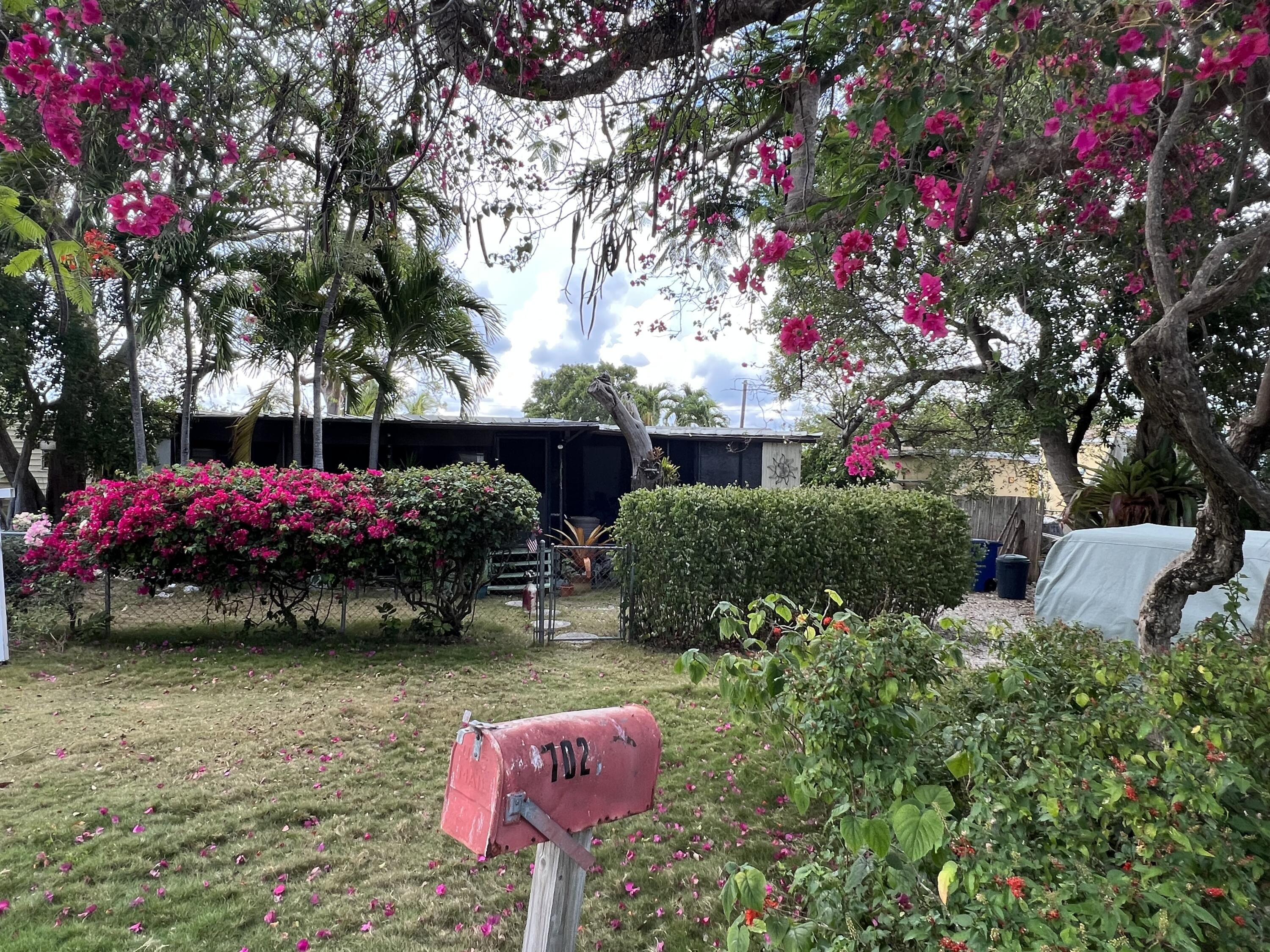 702 Largo Road Key Largo, FL 33037 - Photo 1 of 19 a picture of flowers and cars parked in front of a house