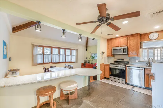 a kitchen with stainless steel appliances a stove a sink a dining table and chairs