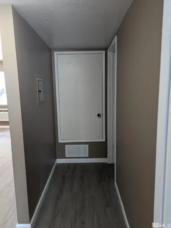 a view of an empty room with wooden floor and closet