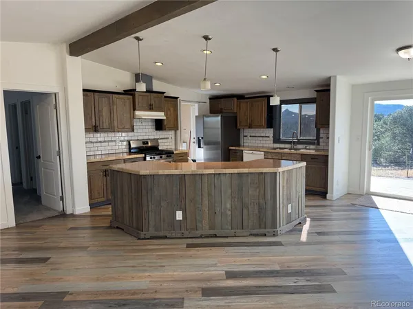 a kitchen with kitchen island stainless steel appliances a stove cabinets and a wooden floor