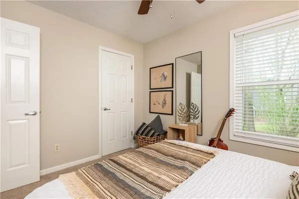 a bedroom with a bed a window and painting on the wall