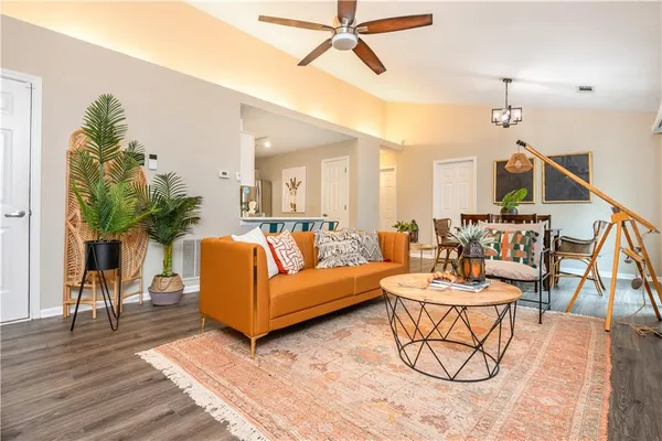 a living room with furniture kitchen view and a wooden floor