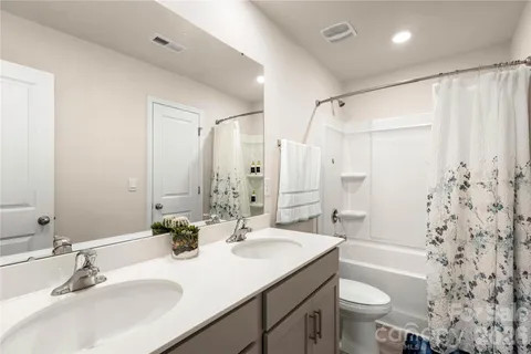 a bathroom with double sink shower bathtub and a toilet