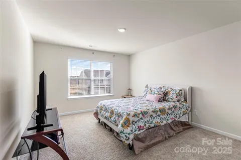 a bedroom with a bed and a flat tv screen on the dresser