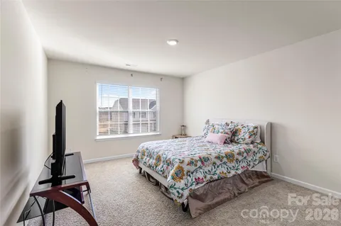 a bedroom with a bed and a flat tv screen on the dresser