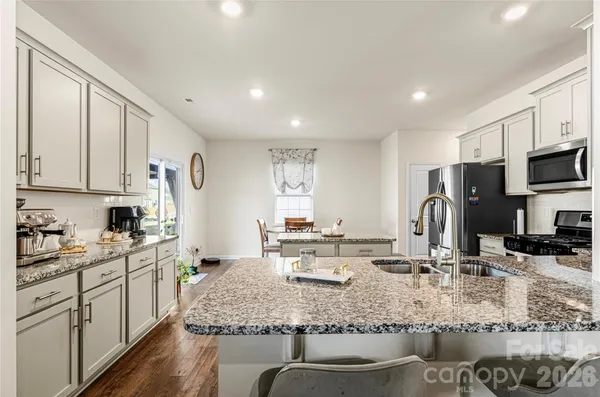a kitchen with stainless steel appliances granite countertop a sink a stove and cabinets