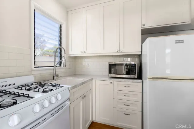 a kitchen with white cabinets and appliances