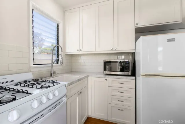 a kitchen with white cabinets and appliances