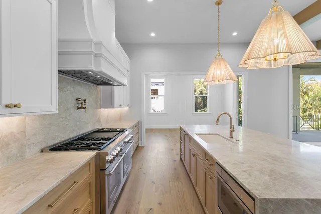 a kitchen with stainless steel appliances granite countertop a sink a stove and a wooden floors
