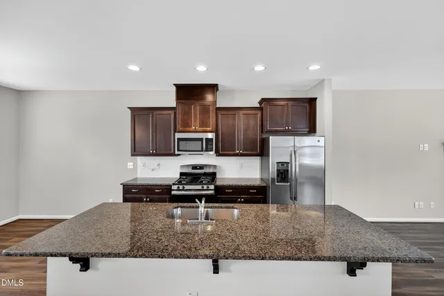 a kitchen with granite countertop a refrigerator a stove and a wooden floors