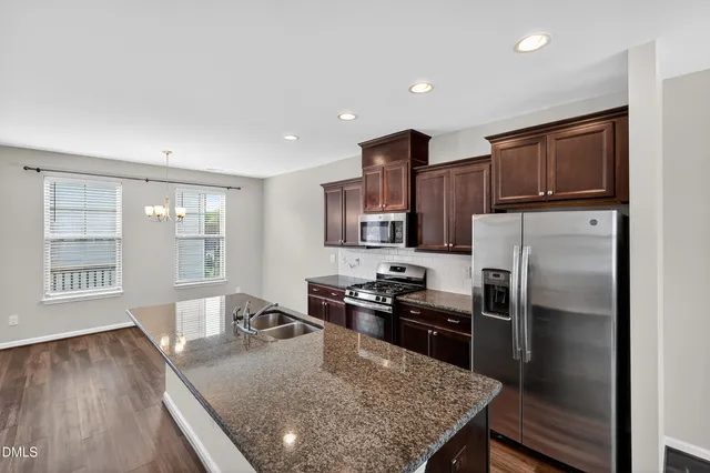 a kitchen with stainless steel appliances granite countertop a sink stove and refrigerator