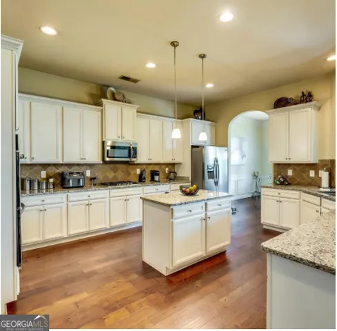a kitchen with stainless steel appliances granite countertop a sink a stove and a refrigerator