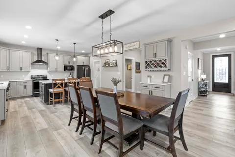 a kitchen with stainless steel appliances granite countertop a dining table chairs refrigerator and microwave