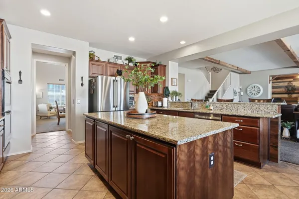 a kitchen with stainless steel appliances granite countertop wooden cabinets a sink a stove a dining table and chairs