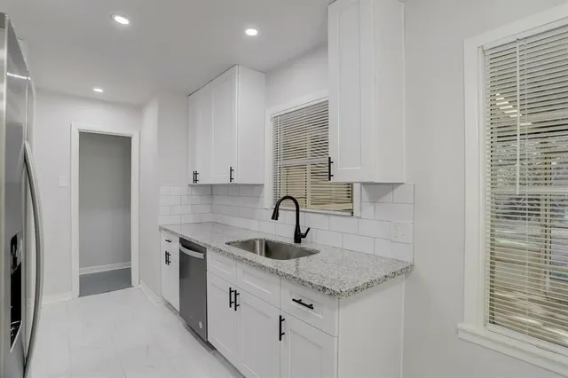 a kitchen with stainless steel appliances granite countertop a sink and a refrigerator