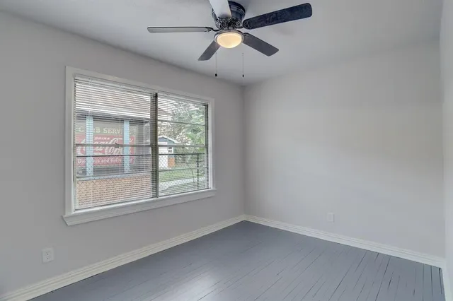 an empty room with a window and a fan