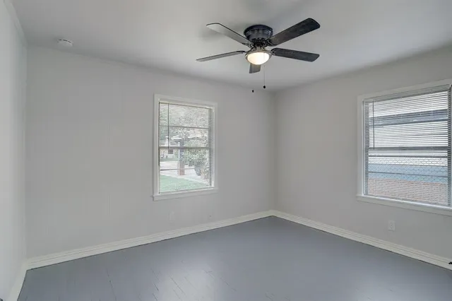 an empty room with a window and a fan