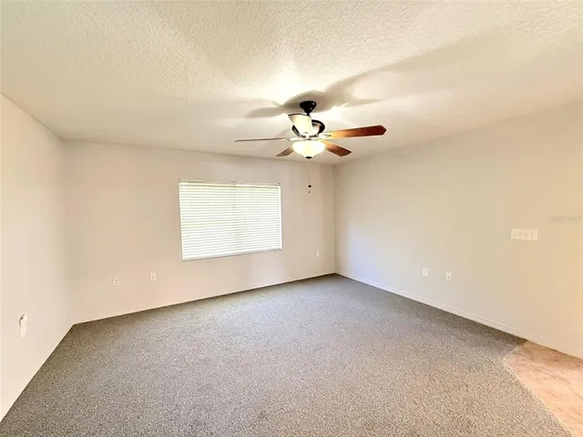 a view of an empty room with a chandelier fan