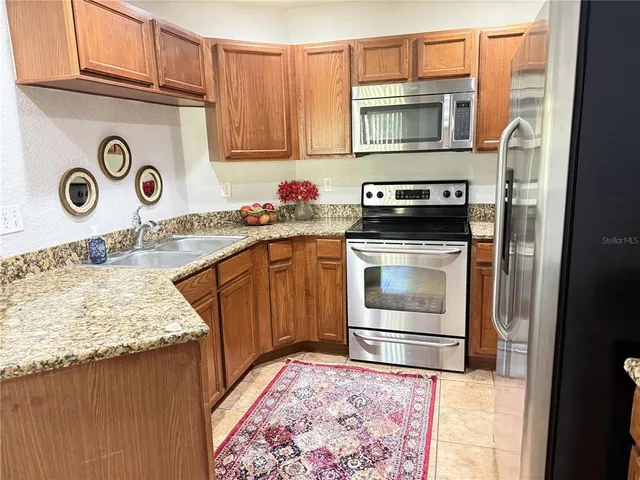a kitchen with granite countertop a stove top oven microwave and cabinets