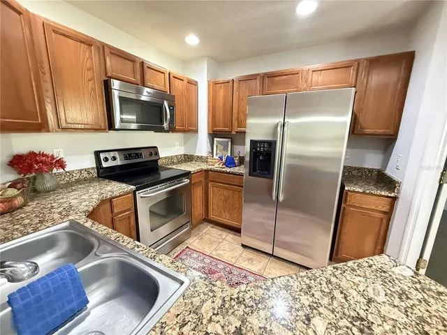 a kitchen with stainless steel appliances granite countertop a refrigerator sink and microwave