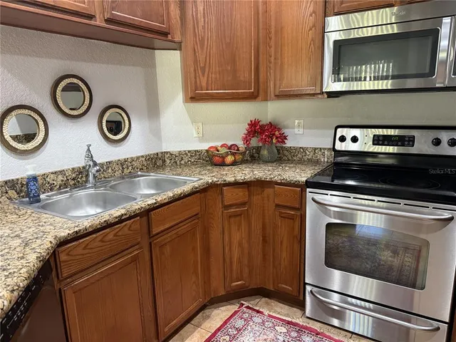 a kitchen with granite countertop stainless steel appliances a stove microwave and sink